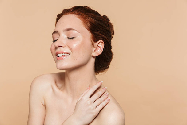 Young redhead woman posing isolated over beige wall background. - Fotó, kép