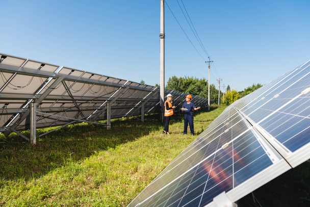Ingenieurin und Geschäftsfrau reden und gehen in der Nähe von Solarbatterien  - Foto, Bild
