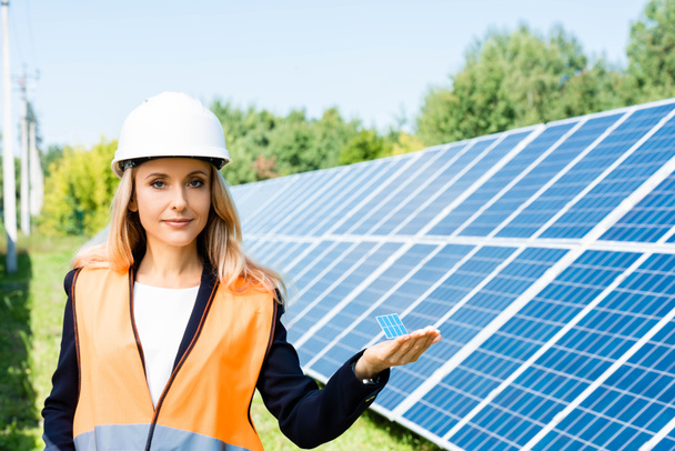 attractive businesswoman in safety vest holding solar battery model  - Photo, Image