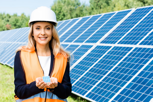 панорамный снимок предпринимательницы в спасательном жилете с моделью солнечной батареи
 - Фото, изображение