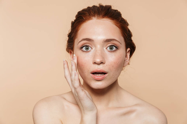 Shocked young redhead woman posing isolated over beige wall background. - Фото, изображение