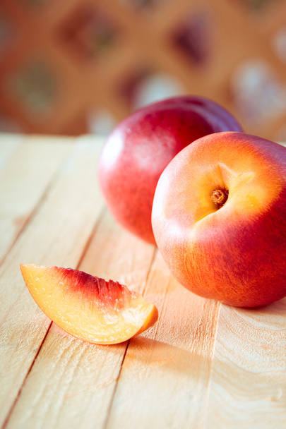 Peaches with a slice of a peach on a wooden table - Photo, Image
