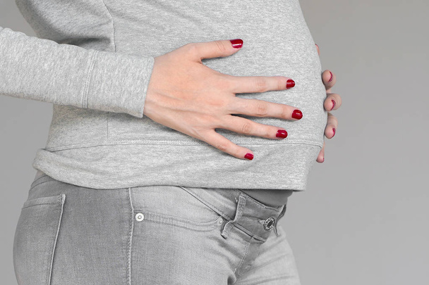 Képek a terhes nőről, amint megérinti a hasát. - Fotó, kép