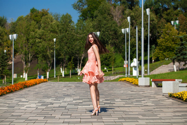 Young beautiful woman in pink dress walking on the summer street - Foto, Imagen