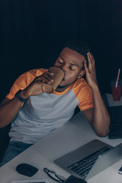 молодой африканский американский программист пьет кофе, чтобы пойти во время работы ночью в офисе
 - Фото, изображение