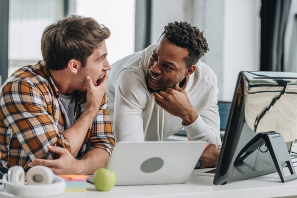 два шокованих мультикультурних програмісти дивляться один на одного під час роботи в офісі разом
 - Фото, зображення
