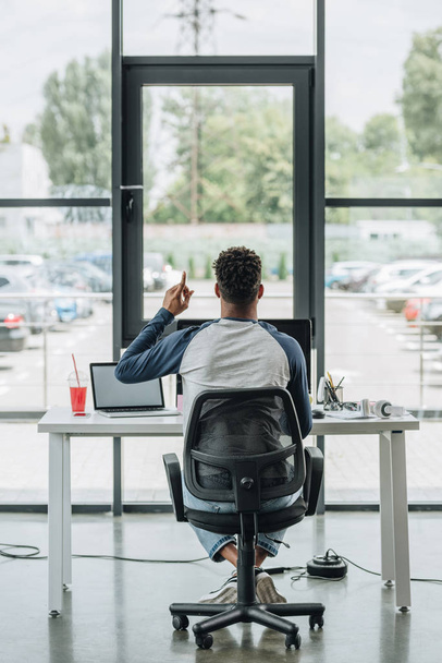 назад взгляд молодого африканского американского программиста, показывающего знак идеи, сидя на рабочем месте в офисе
 - Фото, изображение