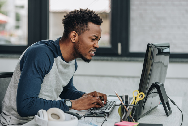 atento programador afroamericano que trabaja en la computadora en la oficina
 - Foto, imagen
