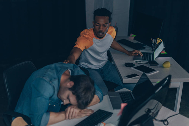joven afroamericano programador despertar colega en la noche en la oficina
 - Foto, imagen