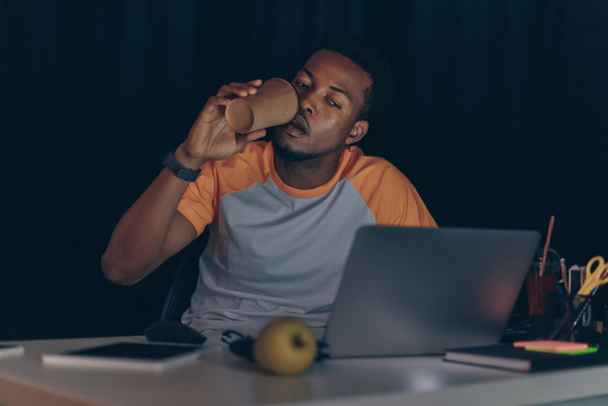 joven afroamericano programador beber café para ir mientras trabaja en la noche en la oficina
 - Foto, imagen
