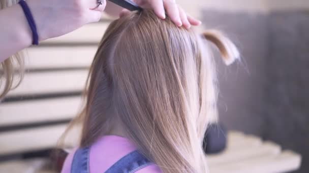 Zöpfe werden zu einem jungen Mädchen geflochten. beim Friseur eine Frisur machen. stylen Sie Ihre Haare. - Filmmaterial, Video