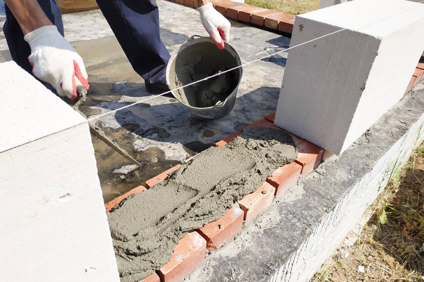 Le travailleur commence la première rangée de construction de maçonnerie en blocs de gaz blanc
. - Photo, image