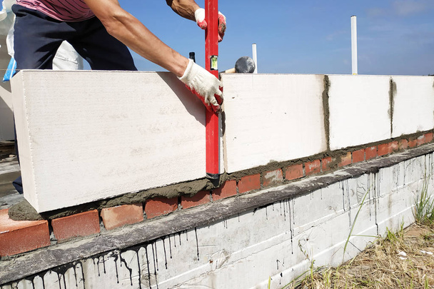 The worker measures the work out wall with a level. - Photo, Image