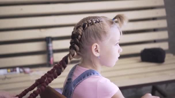 Warkocze są splatane do młodej dziewczyny. Robi fryzurę w fryzjera. Stylizacja włosów. - Materiał filmowy, wideo