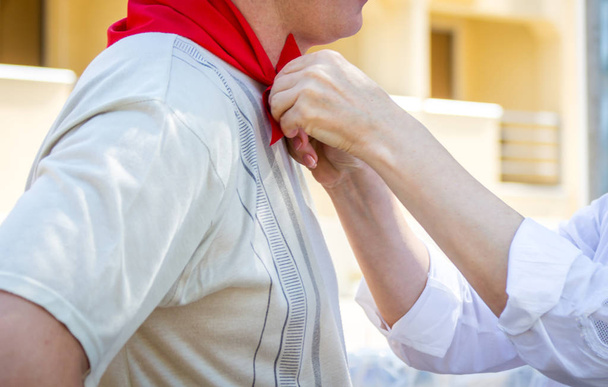 Женщина связывает красный шелковый шейный платок с мужчиной
 - Фото, изображение