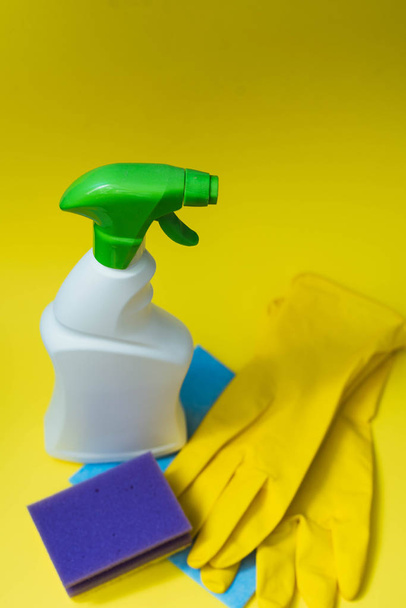 Απορρυπαντικό, σφουγγάρι και γάντια για τον καθαρισμό του σπιτιού σε ένα κίτρινο φωτεινό φόντο. Η έννοια του καθαρισμού, του καθαρισμού και της λεύκανση. - Φωτογραφία, εικόνα