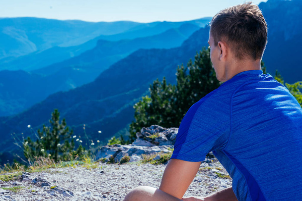 Fit mannelijke fitness trainer chillen op de top van een berg op een sunn - Foto, afbeelding