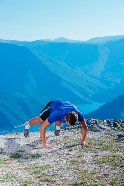 Athlete ( runner ) doing a jumping push up while wearing a blue  - Photo, Image