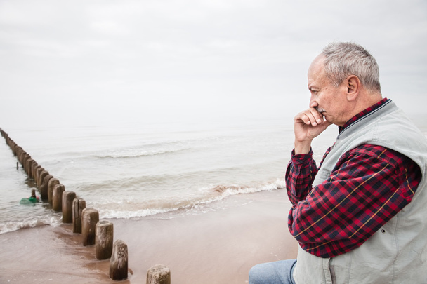 Pensativo homem idoso de pé na praia
 - Foto, Imagem