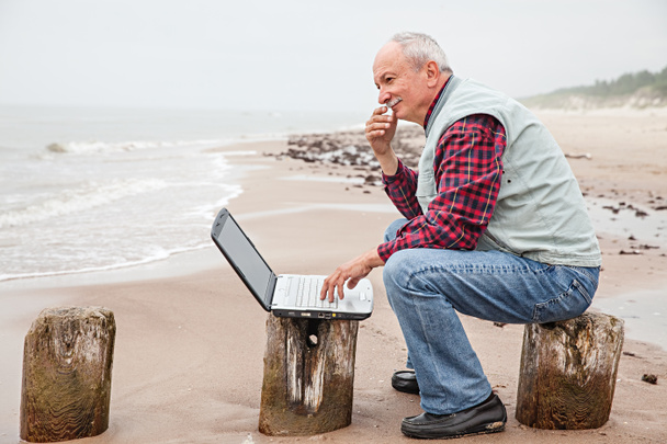 Viejo con cuaderno en la playa
 - Foto, imagen