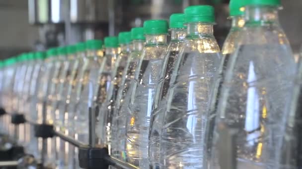 fehér műanyag palackok állnak a víz palackozásra sor, tele ásványvíz, és eltömődött a zöld sapkák - Felvétel, videó