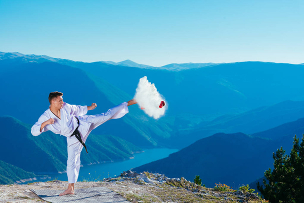 Fit karate athlete kicking a cup filled whit fluor causing a big - Photo, Image