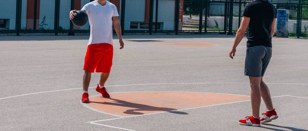 Deux joueurs de basket-ball de rue jouant un sur un lot d'action de gros plan et gardant le ballon
. - Photo, image