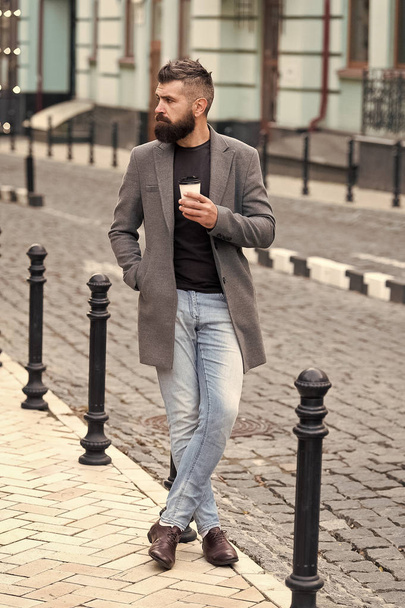 Takeaway coffee. Walk and enjoy fresh hot coffee. Waiting for someone in street. Man bearded hipster drink coffee paper cup. Businessman well groomed enjoy coffee break outdoors urban background - Фото, изображение