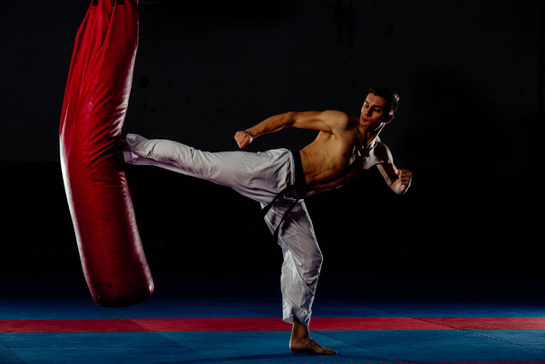 Joven boxeador haciendo un poco de entrenamiento en saco de boxeo en el gimnasio
 - Foto, Imagen