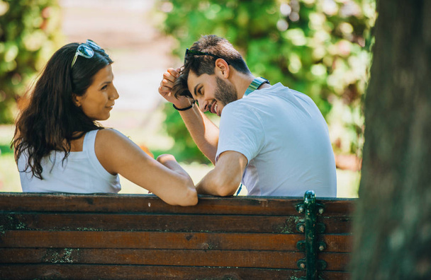 Dating young couple sitting in summer park. Beautiful happy young couple enjoying nature - Photo, Image