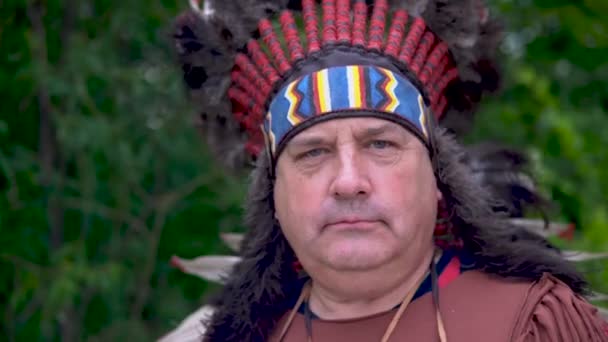 Old Native American Indians stands against the background of the forest with a serious face - Footage, Video