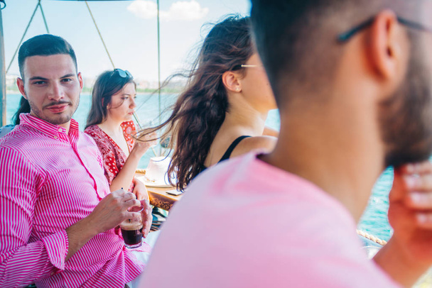 Freunde trinken Kaffee auf einem Boot, während sie chillen und die Sonne genießen. - Foto, Bild