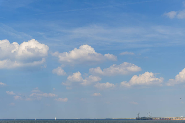 Blick auf den Beginn der Cumulonimbus Wolken während des warmen und nassen Wetters mit dichtem Nebel am Horizont und die Seeseite voller großer Schiffe, scheveningen, Niederlande - Foto, Bild