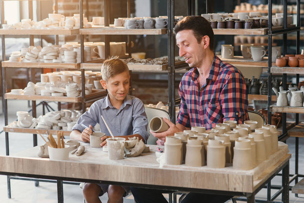 Lindo hombre de mediana edad con su pequeño hijo divirtiéndose en la cerámica
. - Foto, imagen