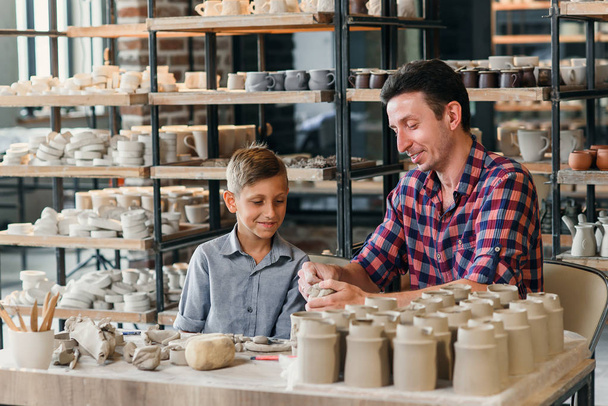 Attractive caucasian man and his cute son having fun in pottery. - Photo, Image