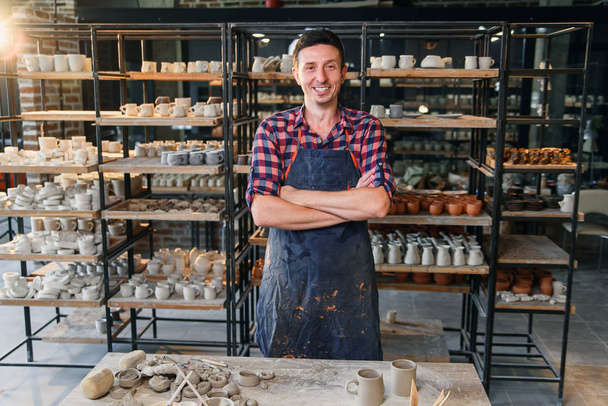 Attractive male potter with crossing hands looking to camera in the pottery. - Foto, Bild