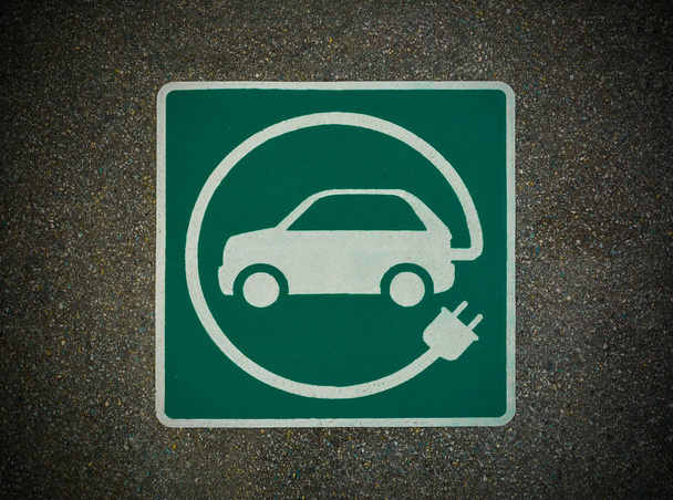 EV-znak stacji ładowania pojazdów elektrycznych. Znak E na fakturze asfaltu - Zdjęcie, obraz