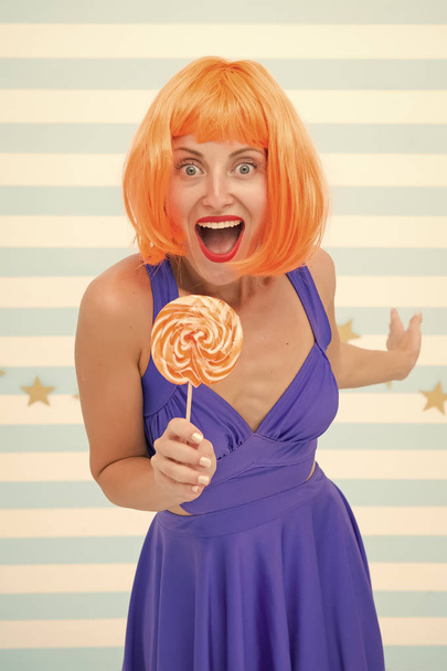 happy pinup model with lollipop in hand. Fashion girl with orange hair having fun. Cool girl with lollipop. Sexy woman. Crazy girl in playful mood. Sweet look. So much fun. Going crazy. Enjoy party - Фото, изображение