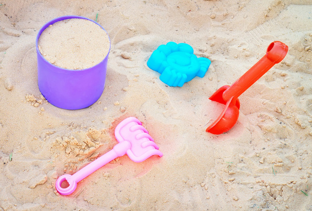 Ensemble de jouets en plastique coloré sur un sable. Bac à sable
 - Photo, image