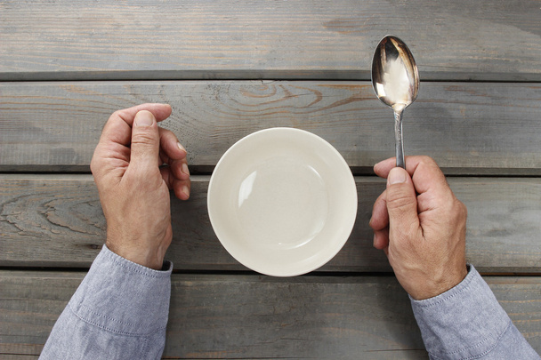 Hungry man waiting for his meal over empty bowl on wooden table. - Photo, image