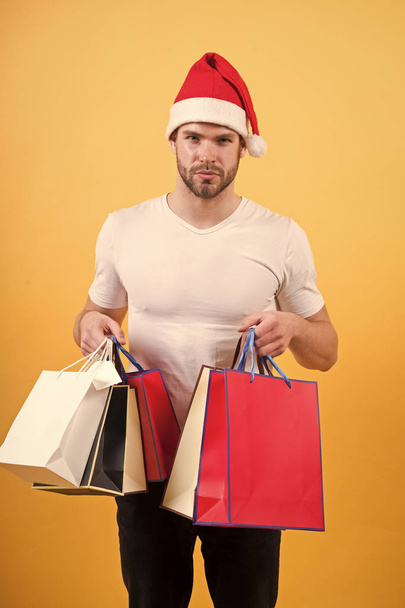 online christmas shopping. Happy new year. The morning before Xmas. happy santa man on yellow wall. delivery christmas gift. man in santa hat hold christmas present. Merry Christmas. Choosing present - Foto, afbeelding
