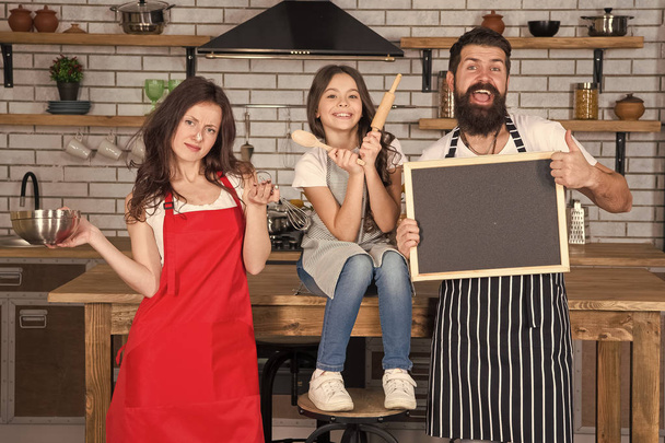 Cooking together. Family mom dad and daughter wear aprons stand in kitchen. Cooking food concept. Prepare delicious meal. Breakfast time. Family having fun cooking together. Teach kid cooking food - Фото, зображення