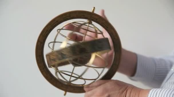Un hombre sostiene y hace girar un modelo de una esfera armilar
 - Metraje, vídeo