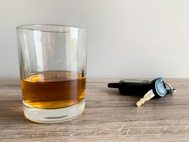 Drunk driving concept. Glass with whiskey and car key on the table. - Fotoğraf, Görsel