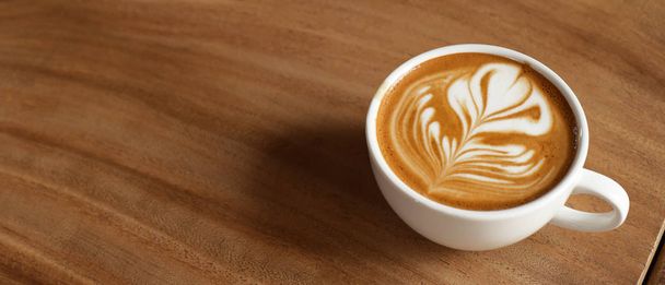 a cup of latte art coffee on wooden background                               - Φωτογραφία, εικόνα