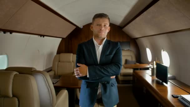 Confident business man with crossed arms inside of private jet seriously looking at You - Footage, Video