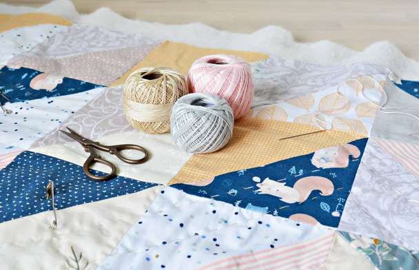Hand stitch quilting process: cotton thread, needle and scissors on the table - Фото, зображення
