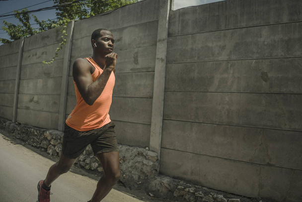 urban runner workout . Young attractive and athletic black African American man running outdoors on asphalt road training hard jogging in sport and healthy lifestyle - Fotografie, Obrázek