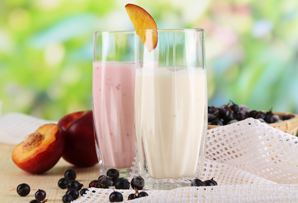 Delicious milk shakes with blackberry and peach on wooden table on natural background - Фото, зображення