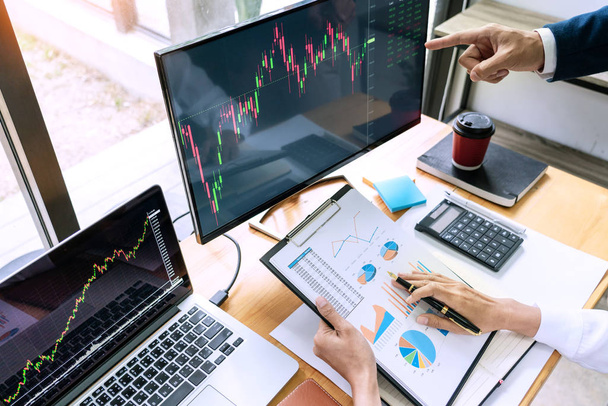株式ブローカーのチーム ディスプレイ画面で議論投資のための株式市場取引のデータ、グラフやレポートを分析  - 写真・画像